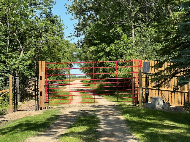 A Lift & Go solar gate securing a property in a wooded area with deer nearby.